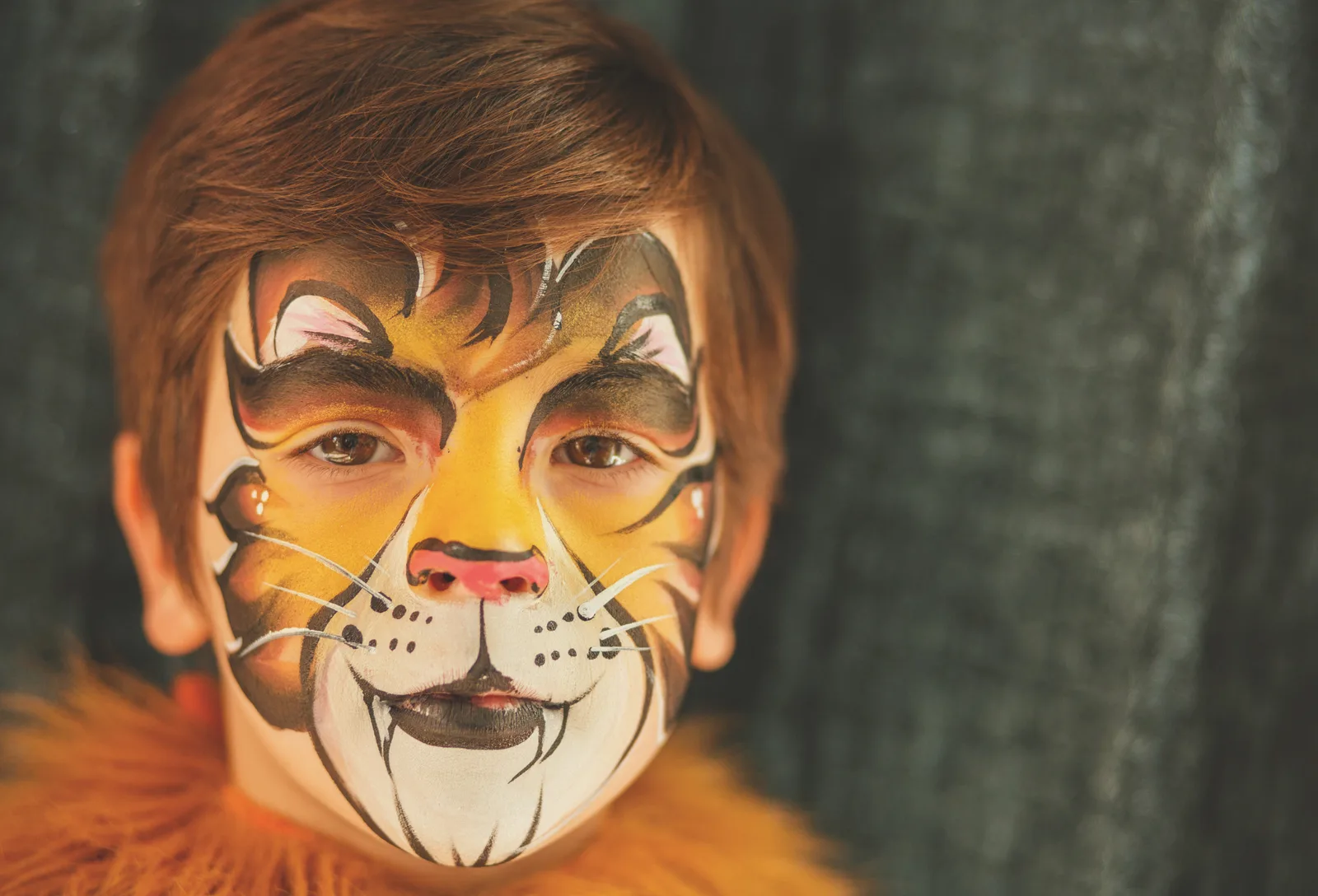 Close-up of a child with full-face tiger face painting.