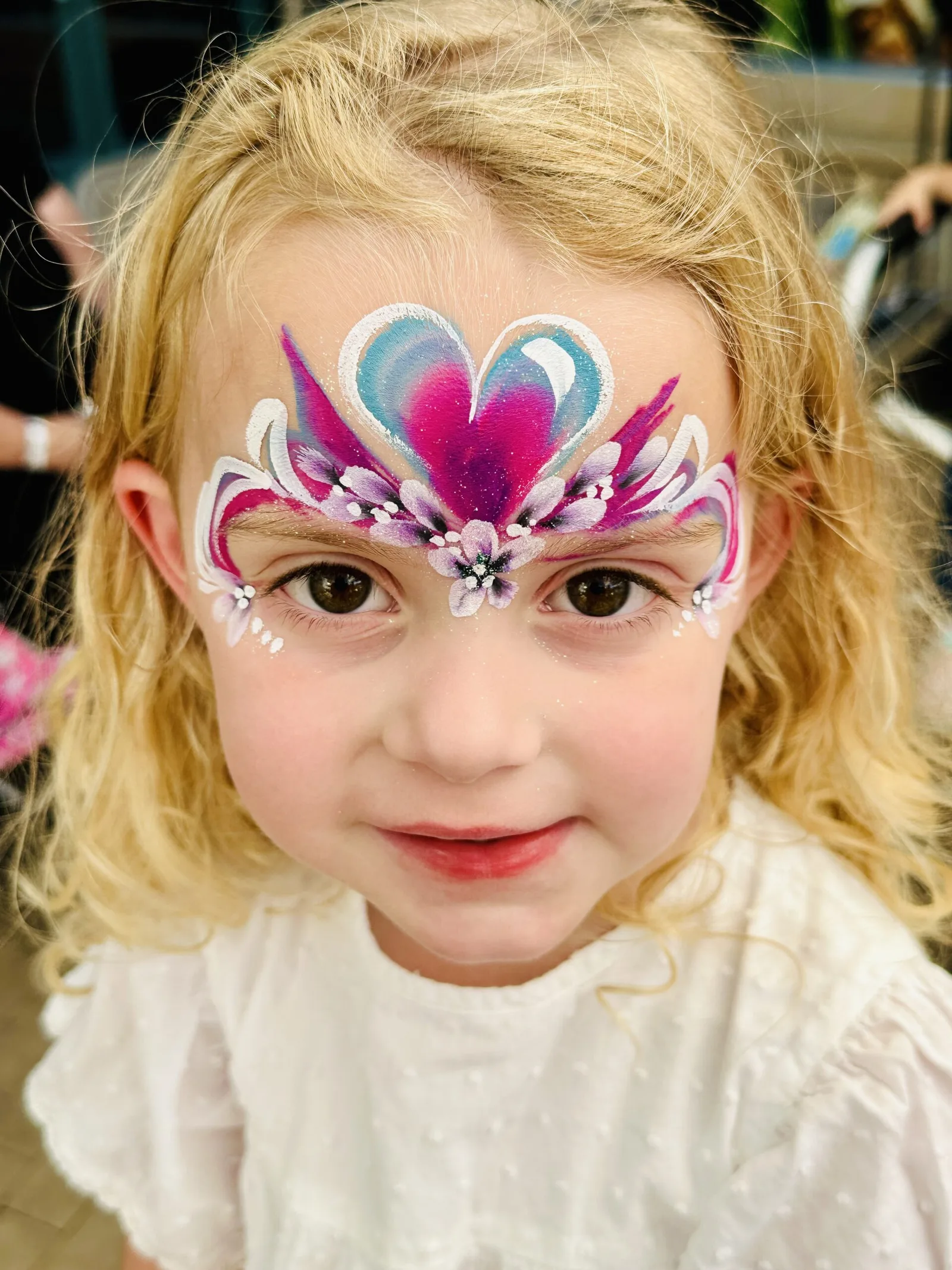 Child with pink princess mask face painting.