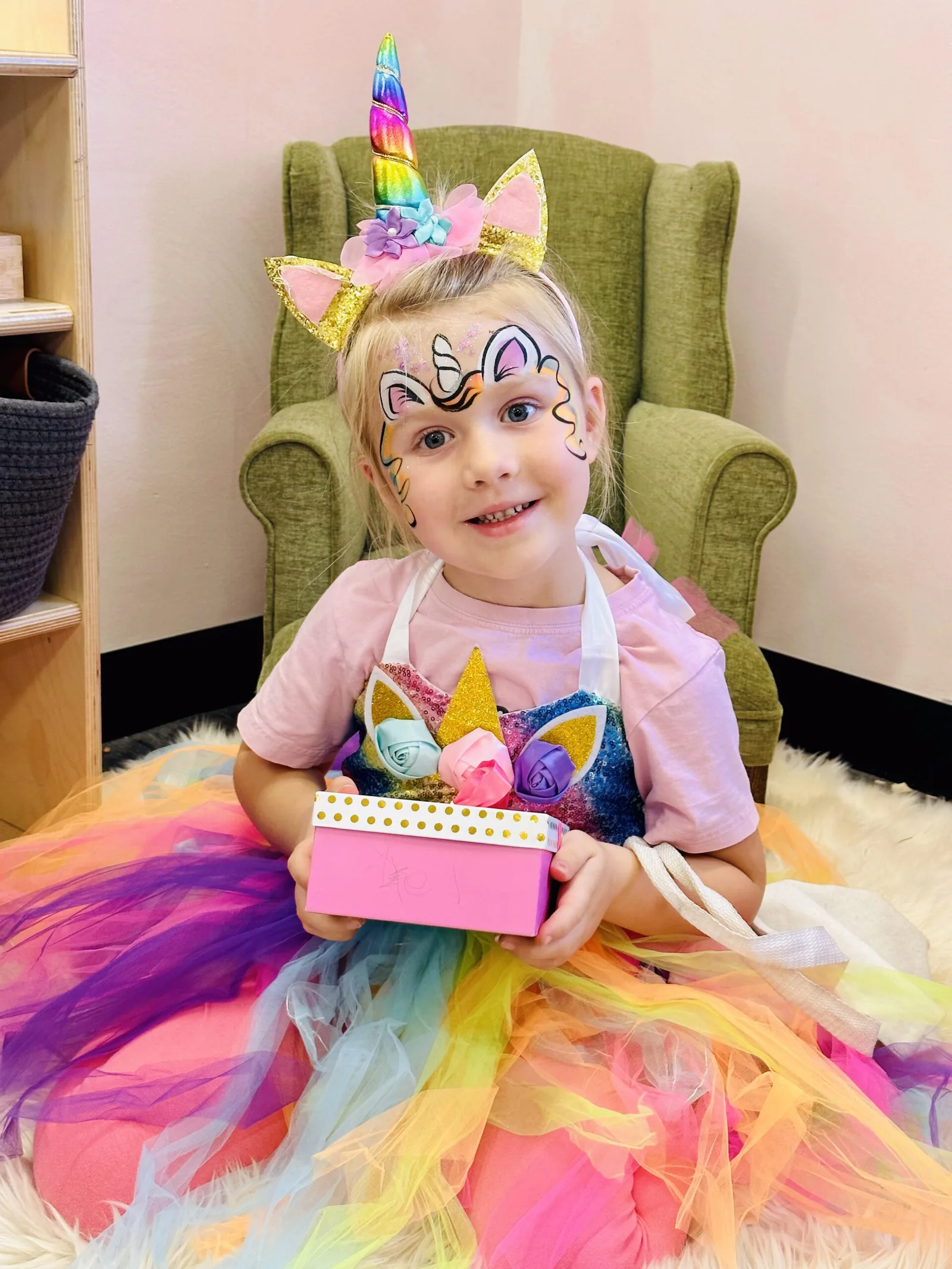 Child in a unicorn birthday outfit with unicorn face painting.