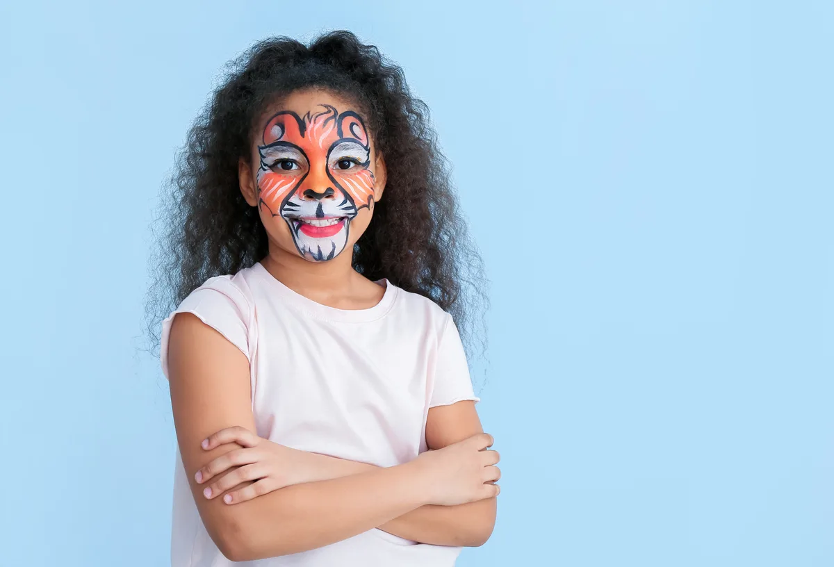 Girl with tiger face painting on a blue studio background.