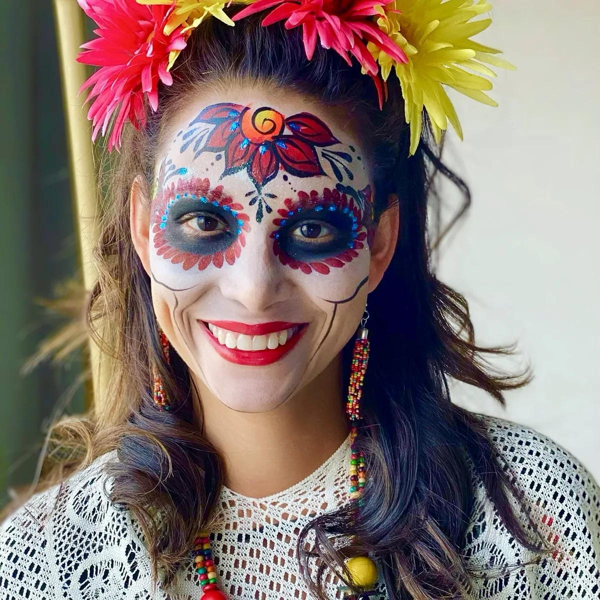 Woman with Day of the Dead skull face painting and a floral headdress.
