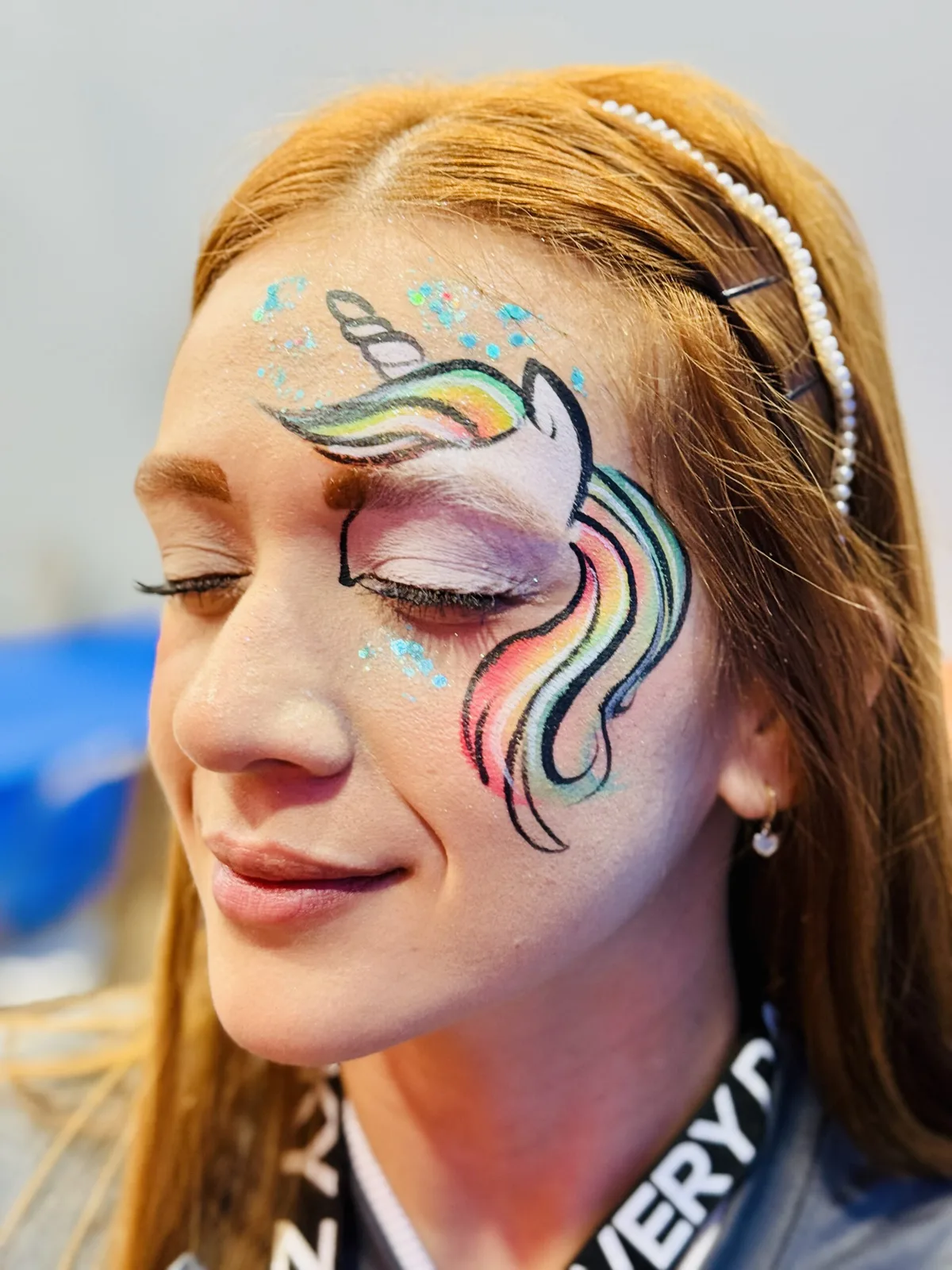 Woman with rainbow unicorn face painting close-up.
