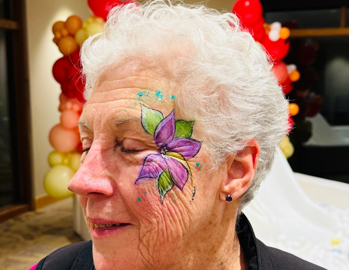 Adult with purple butterfly face painting closeup.